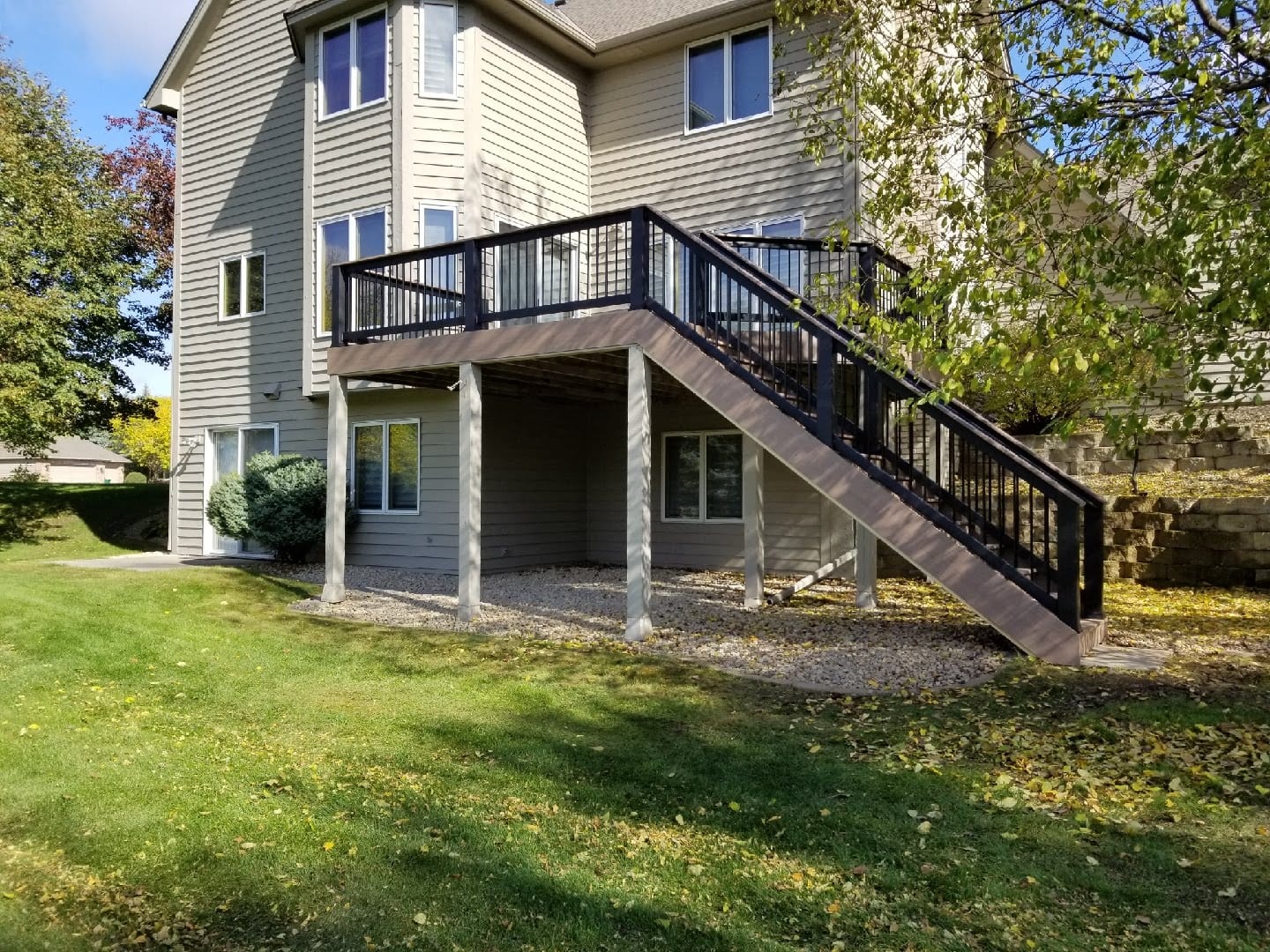 after picture of new raised deck with black railings and descending stairs to yard