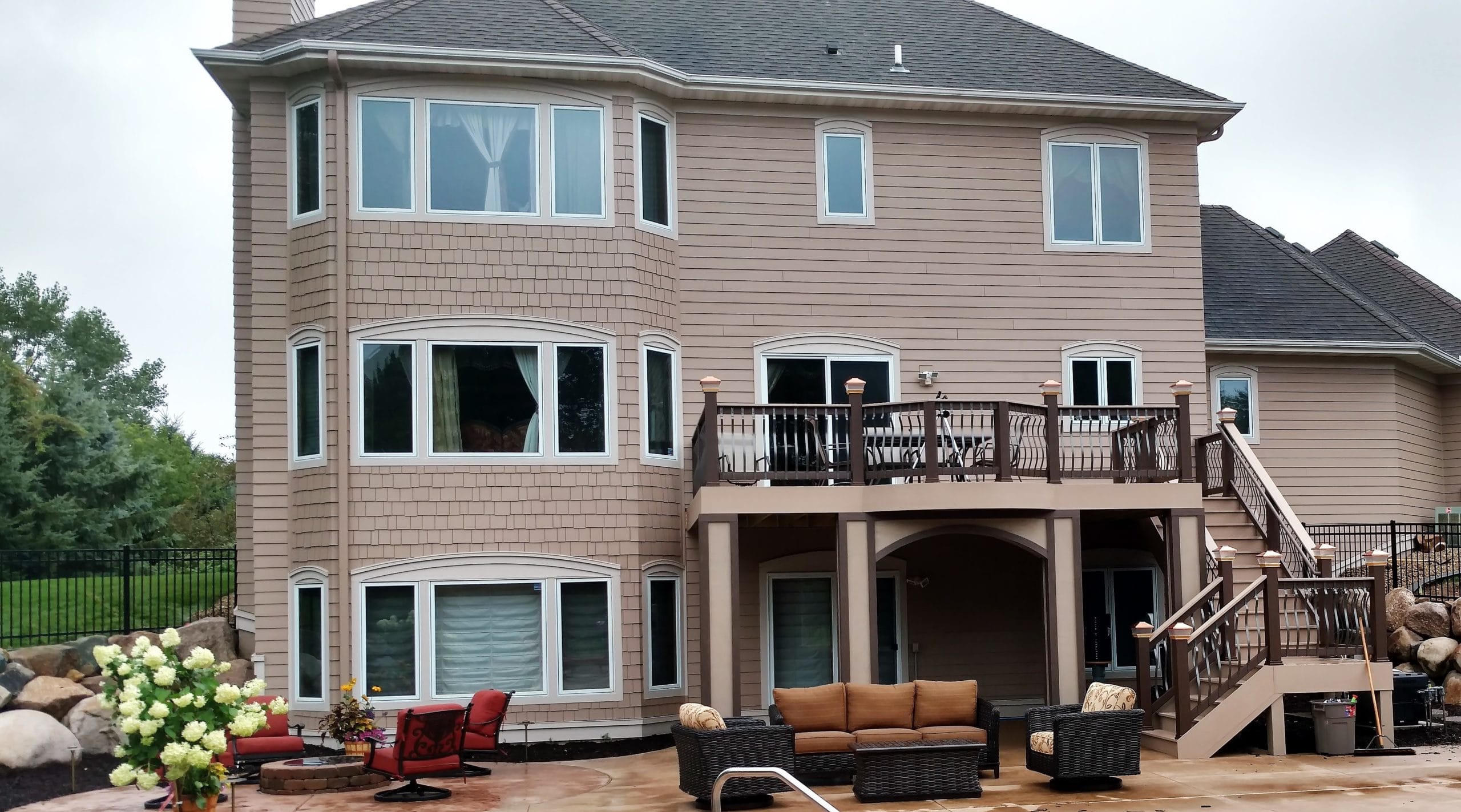 back side picture of a house with a new deck descending to a pool area