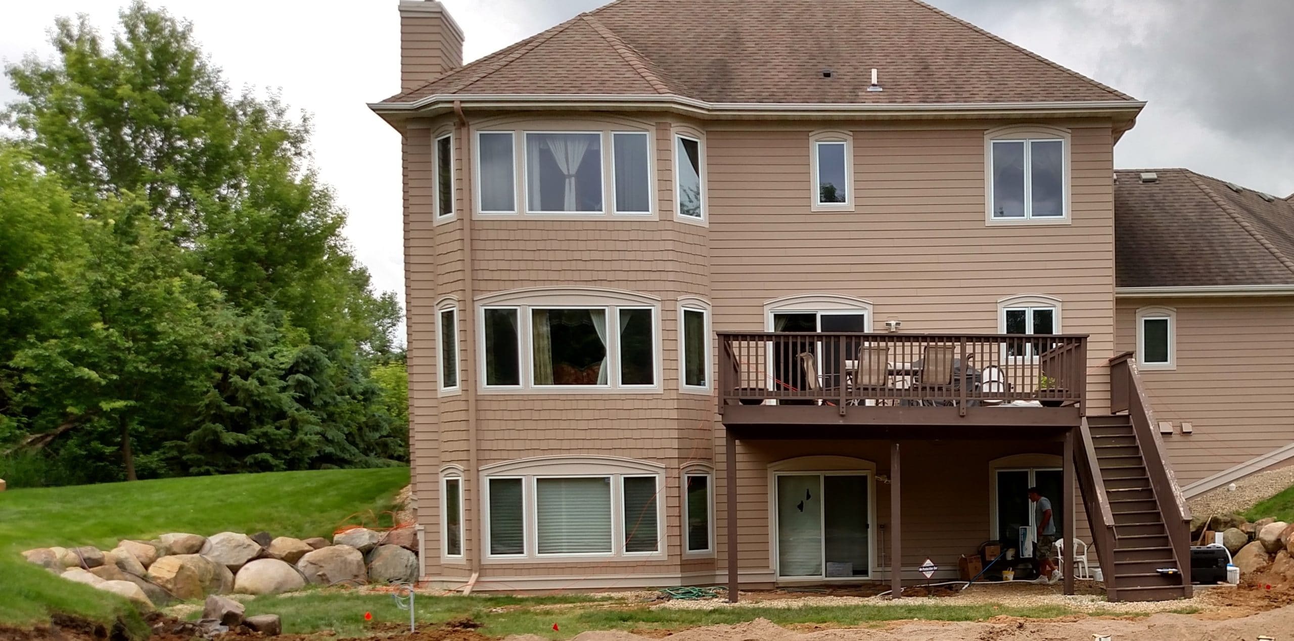 back side picture of a house with a new deck descending to a pool area