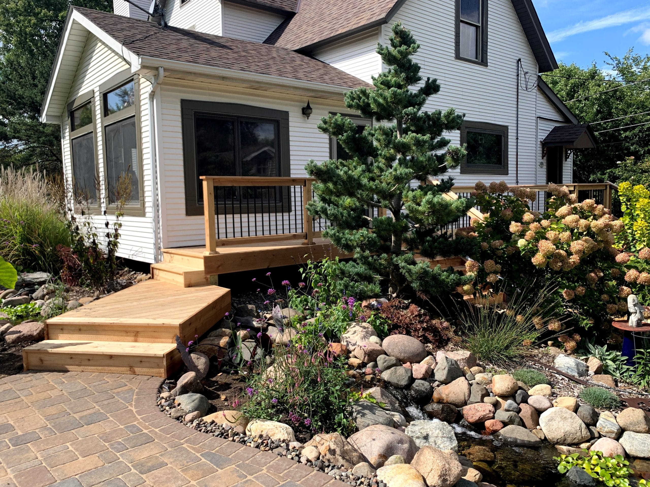 new wooden deck surface next to a garden with the house in the background