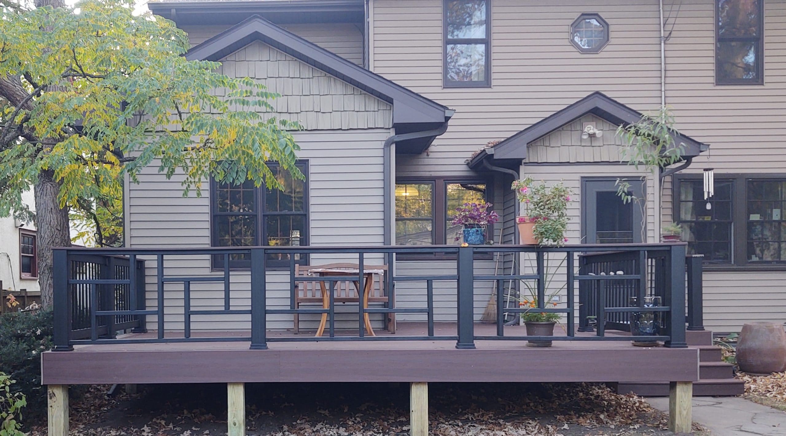 new square slightly raised deck with black railings and assorted potted plants