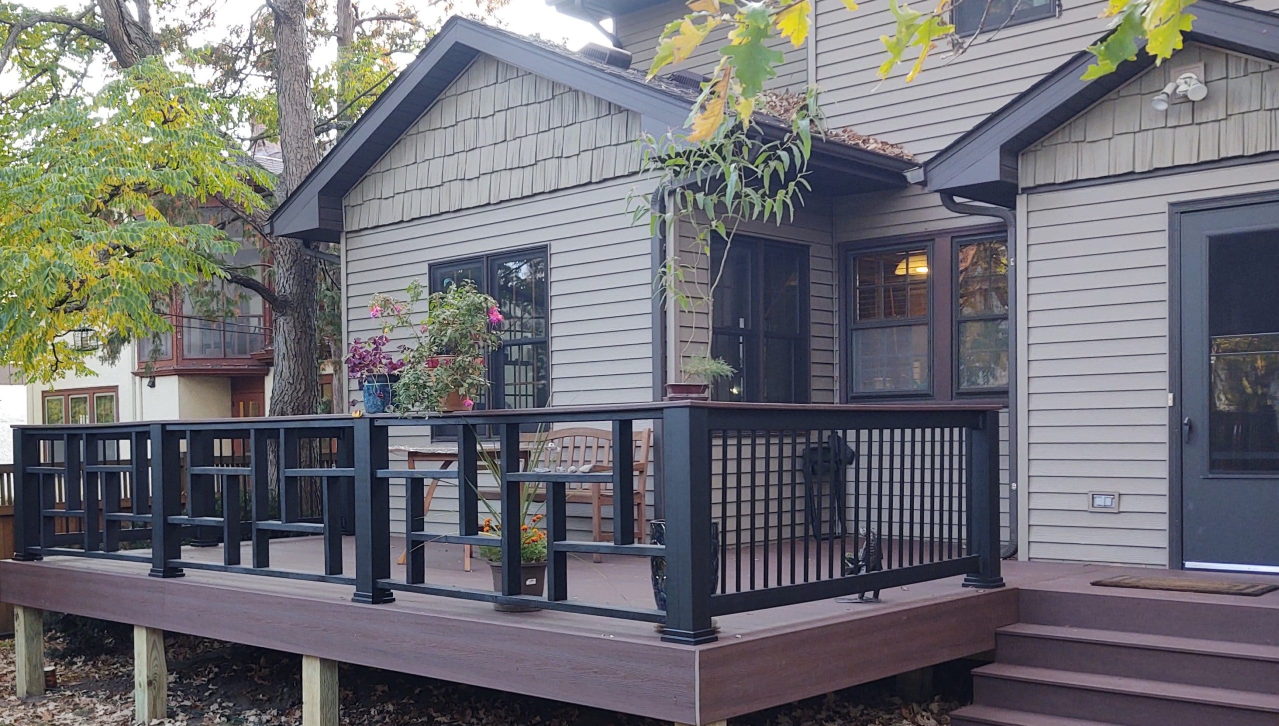 new square slightly raised deck with black railings and assorted potted plants