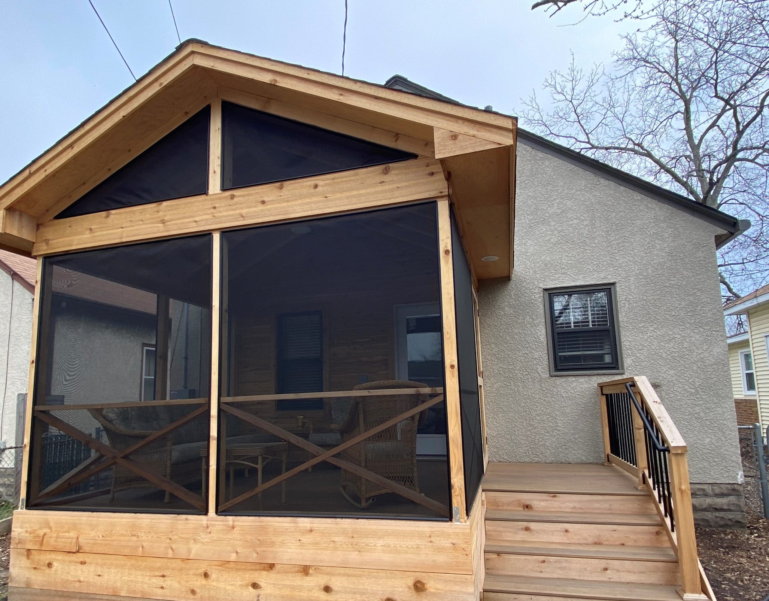Wooden screened in porch with a short staircase descending to a ground patio
