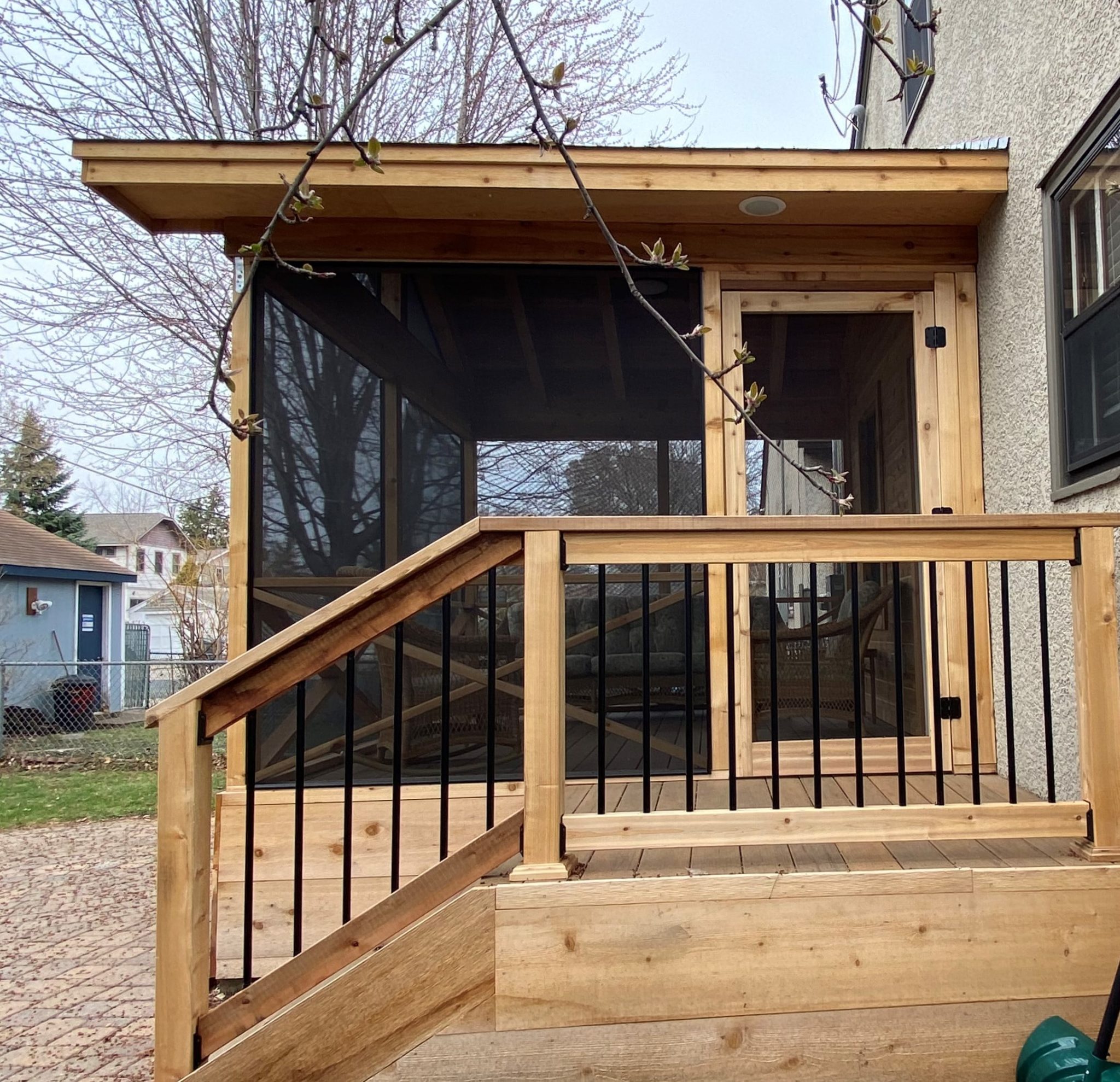 Wooden screened in porch with a short staircase descending to a ground patio